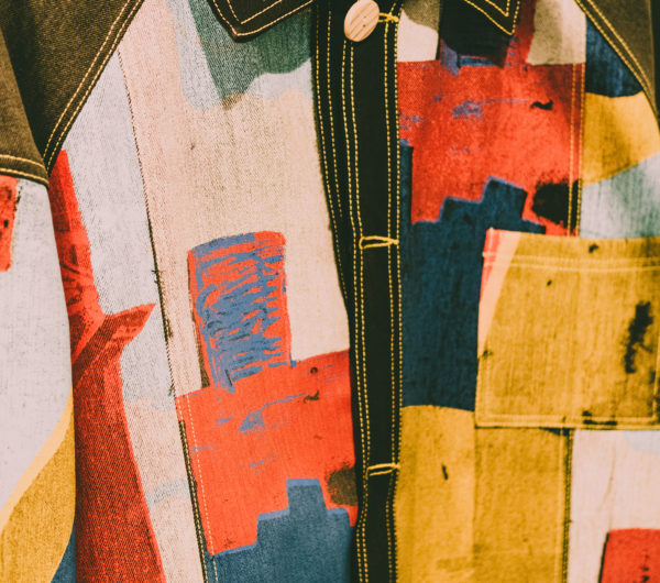 A jacket designed by Bethany Williams shown in a close up detail. The jacket is made using printed denim fabrics.