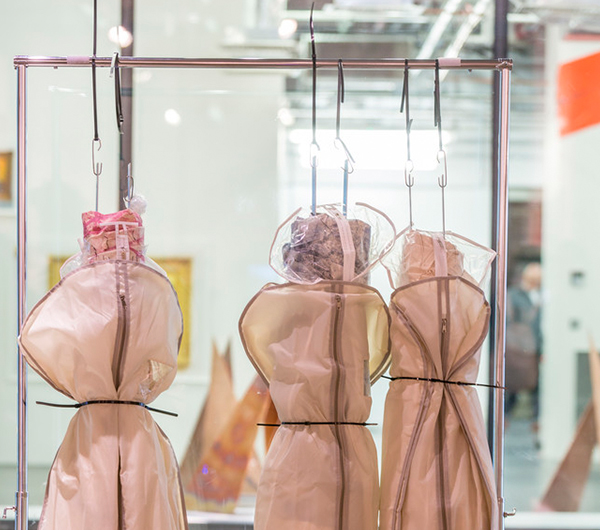 Three dummies are covered in garment bags hung onto the rail and tied in the middle with a string