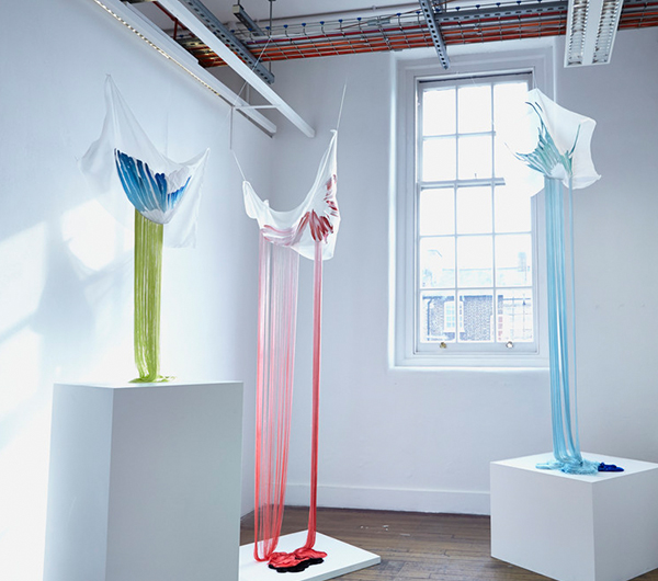 A collection of three textile pieces shown in a gallery space hung off the ceiling
